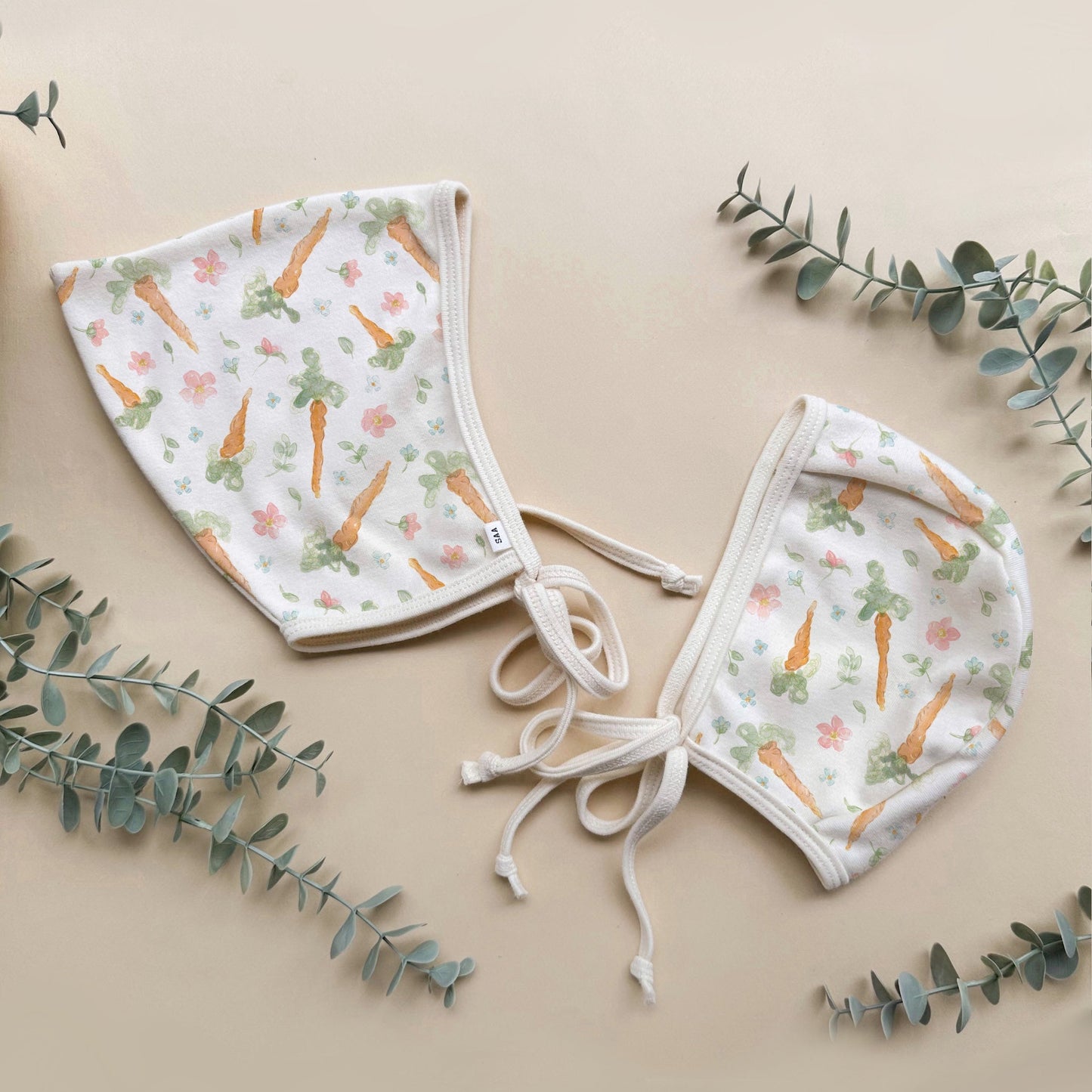 Baby bonnet with carrot pattern on a beige background