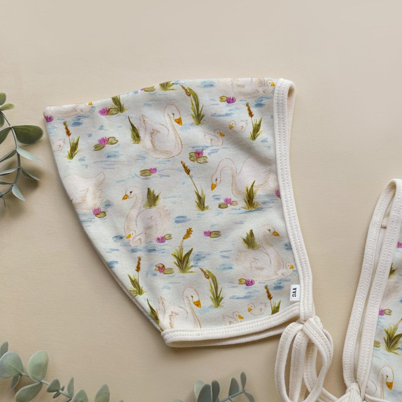 Baby bonnet with swan pattern on a beige background