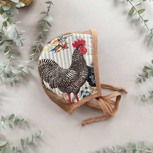 Bonnet with a rooster design on a light background with eucalyptus leaves.