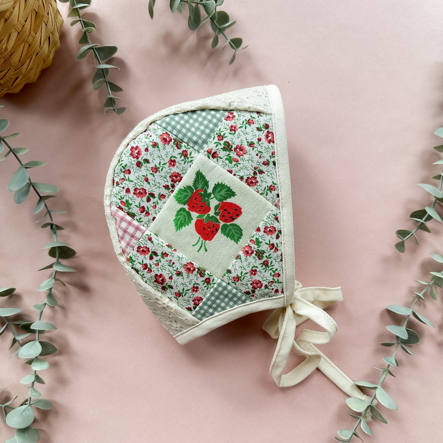 Floral patchwork baby bonnet with red roses on a pink background
