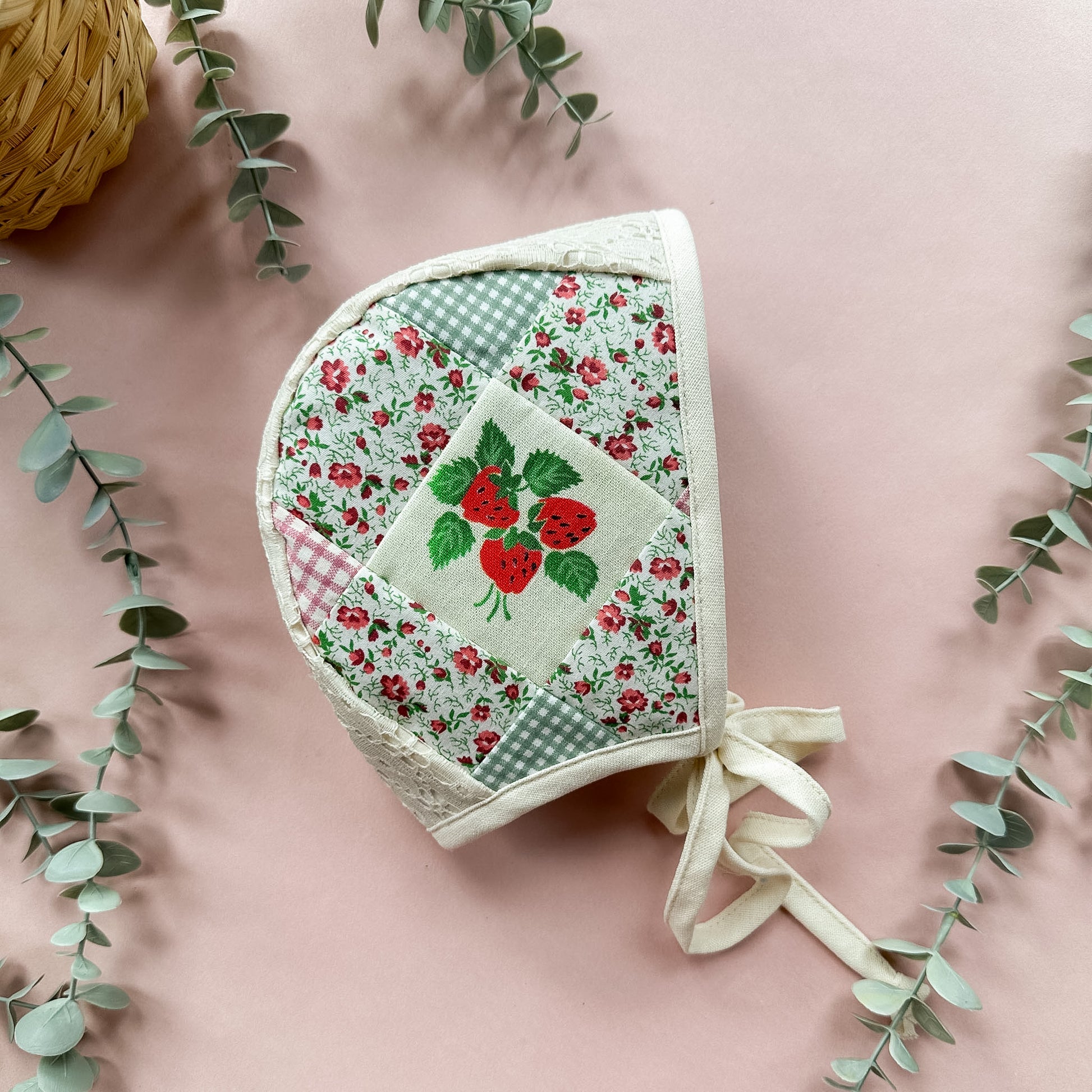 Floral patchwork baby bonnet with red roses on a pink background