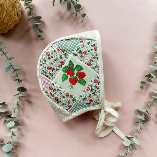 Floral patchwork baby bonnet with red roses on a pink background