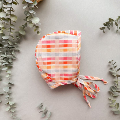 Colorful checkered bonnet on a light gray background with green leaves
