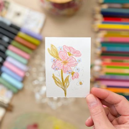Hand holding a card with a floral design in front of colorful markers. ACEO original artwork by Carrie Keefe - Bloom by April